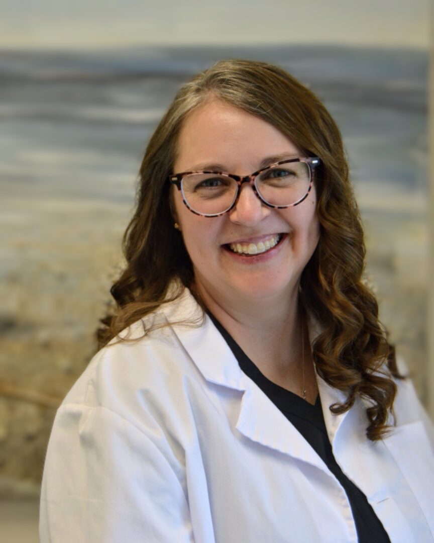 Smiling woman in glasses and white lab coat.
