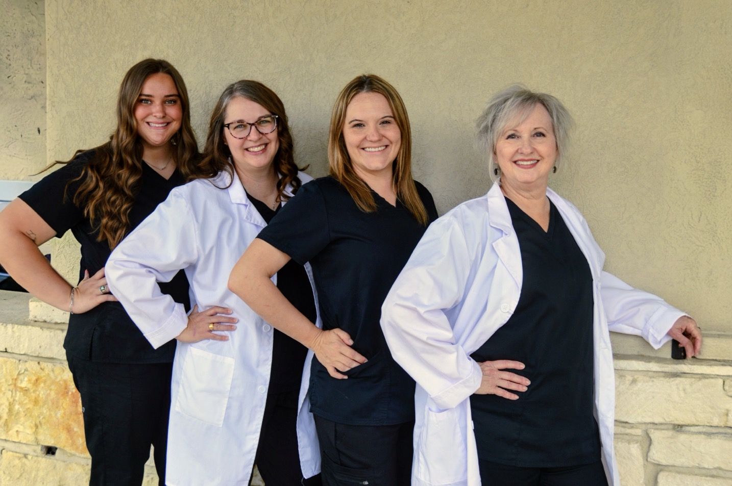 Four women in medical attire posing confidently against a plain background.
