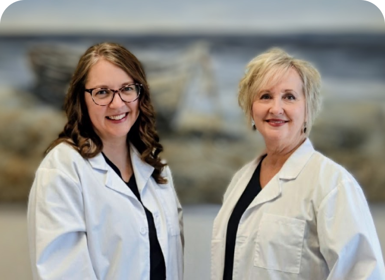 Two female doctors in white coats smiling at the camera.